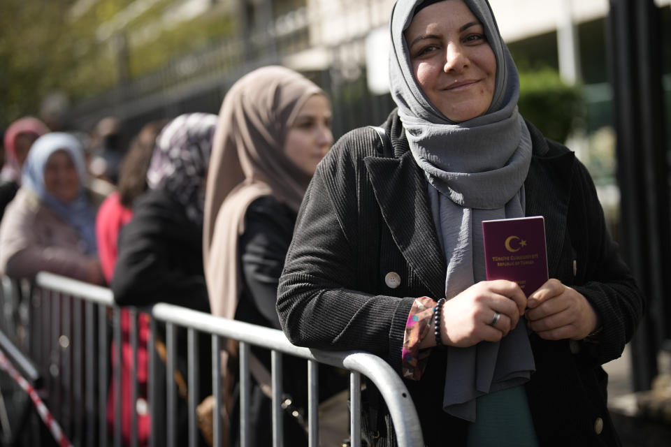 A Turkish citizen holds her passport as she queues to vote, outside the Turkish consulate, Thursday, April 27, 2023 Boulogne-Billancourt, outside Paris. The voting for the upcoming Turkish election begins on Thursday, with Turkish overseas citizens being the first ones allowed to cast their ballots at embassies and consulates. Turkey votes on Sunday in presidential and parliamentary elections that could extend the increasingly authoritarian President Recep Tayyip Erdogan's two-decades in power or tilt the country toward what his opponents promise to a more democratic one. (AP Photo/Christophe Ena)