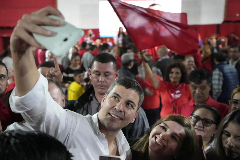 Santiago Peña, candidato presidencial por el gobernante Partido Colorado, se toma una selfie con un simpatizante durante un mitin en Villa Elisa, Paraguay, el miércoles 26 de abril de 2023. Las elecciones generales de Paraguay están programadas para el 30 de abril. (AP Foto/Jorge Saenz)