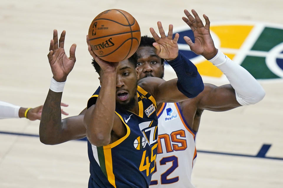 Utah Jazz guard Donovan Mitchell (45) passes the ball as Phoenix Suns center Deandre Ayton (22) defends during the first half of an NBA basketball game Thursday, Dec. 31, 2020, in Salt Lake City. (AP Photo/Rick Bowmer)