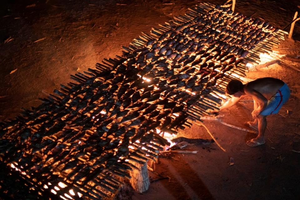 A Yawalapiti man cooks fish during the Kuarup funeral ritual (Reuters)