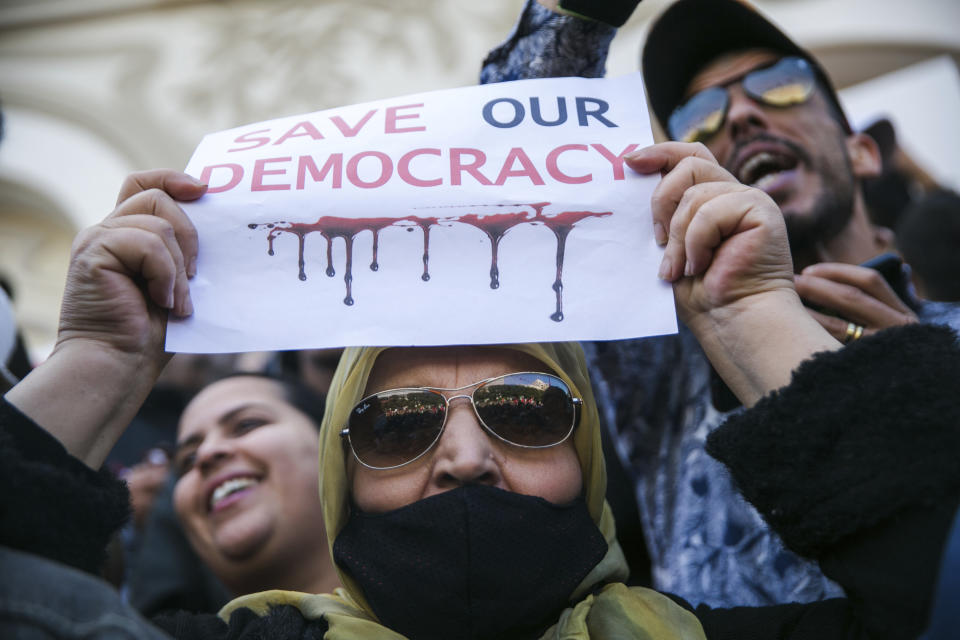 FILE - A woman holds up a banner during a protest against Tunisian President Kais Saied, in Tunis, Tunisia, Sunday, April 10, 2022. Despite an election debacle, Tunisia's increasingly authoritarian president appears determined to upend the country's political system, threatening to unravel the fragile democracy and collapse the economy in the North African nation that a decade ago stood out as a model of good governance and economic prosperity in the aftermath of the Arab Spring protests. (AP Photo/Hassene Dridi, File)