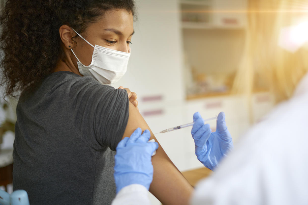 Close up portrait of beautiful young woman wearing mask getting vaccinated.