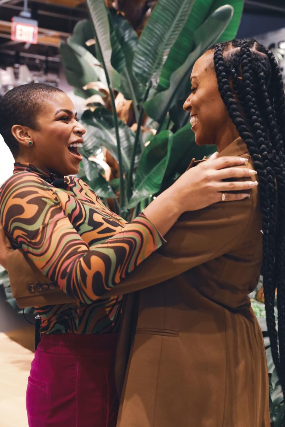 Two Black women smile big and embrace each other