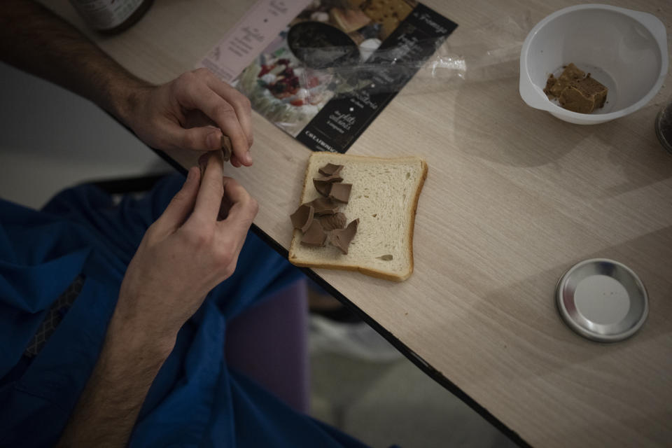 A nurse makes a chocolate sandwhich in the COVID-19 intensive care unit at the la Timone hospital in Marseille, southern France, Friday, Dec. 24, 2021. Marseille's La Timone Hospital has weathered wave after wave of COVID-19 and allows families to visit gravely ill loved ones in the ICU. One patient spending the holidays there said he deeply regrets not getting vaccinated against the coronavirus. (AP Photo/Daniel Cole)