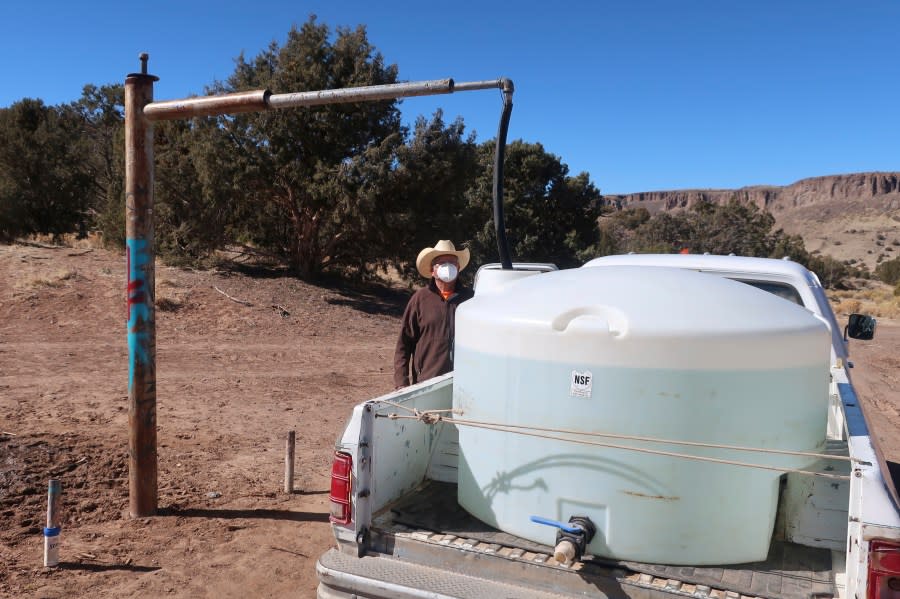 FILE – Phillip Yazzie waits for a water drum in the back of his pickup truck to be filled in Teesto, Ariz., on the Navajo Nation, on Feb. 11, 2021. (AP Photo/Felicia Fonseca, File)