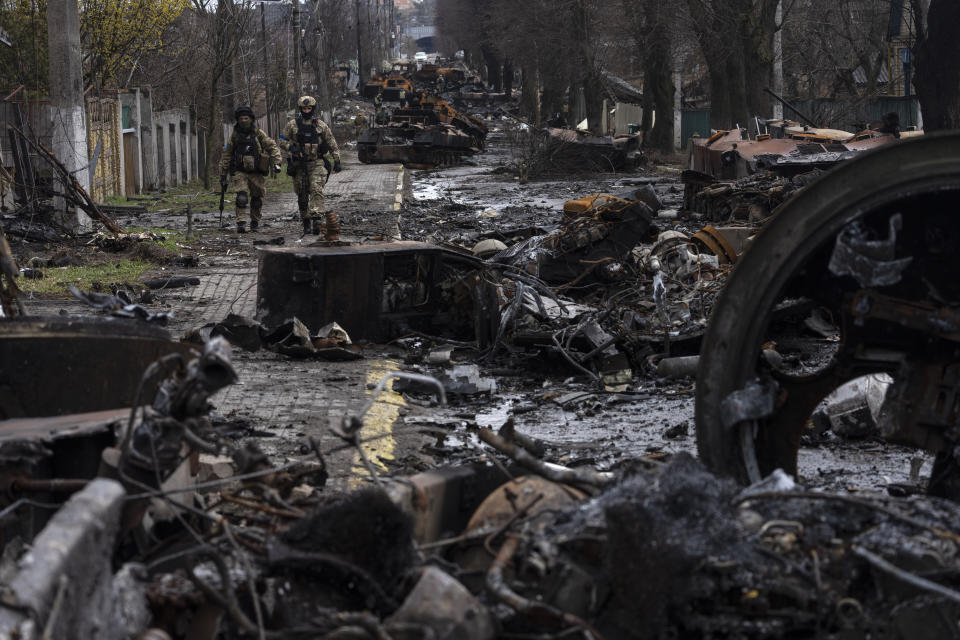 FILE - Soldiers walk amid destroyed Russian tanks in Bucha, in the outskirts of Kyiv, Ukraine, April 3, 2022. Eight months after Russian President Vladimir Putin launched an invasion against Ukraine expecting a lightening victory, the war continues, affecting not just Ukraine but also exacerbating death and tension in Russia among its own citizens. (AP Photo/Rodrigo Abd, File)
