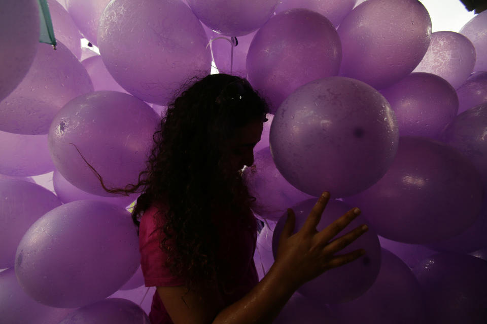 A woman takes cover from the rain next to balloons to symbolize their prayers for the 239 passengers on board the missing Malaysia Airlines flight MH370, at a park at Kuala Lumpur, Malaysia, Sunday March 30, 2014. A new batch of relatives from China has arrived today to seek answers of what happened to their loved one on board flight MH370. (AP Photo/Aaron Favila)