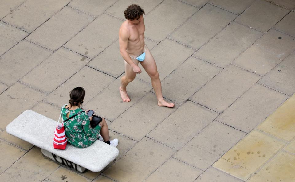 A man wearing a surgical mask as G-string walks past a woman, as the spread of the coronavirus disease (COVID-19) continues, on Oxford Street in London, Britain July 24, 2020. REUTERS/Simon Dawson