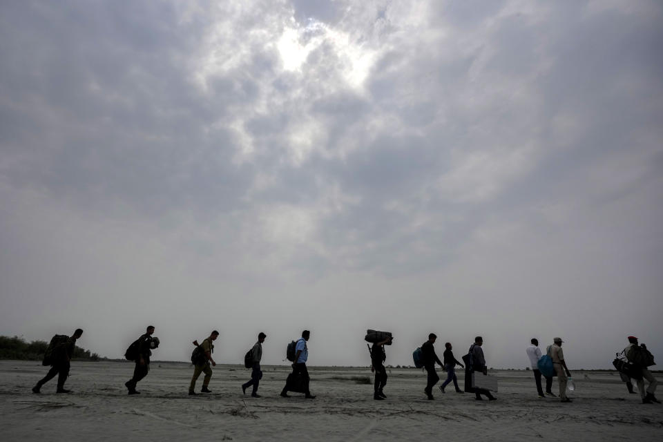 Polling officials carry Electronic Voting Machines (EVMs) across a dried riverbed of Brahmaputra on the eve of the national election at Baghmora Chapori (small island) of Majuli, about 350km (218 miles) east of the state capital Guwahati, India, Thursday, April 18, 2024. (AP Photo/Anupam Nath)