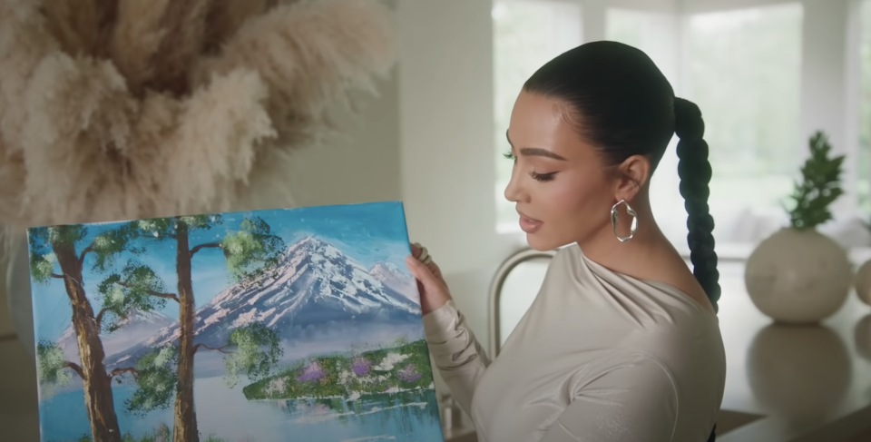 Kim holding up a mountain-scape painting done by her daughter, North