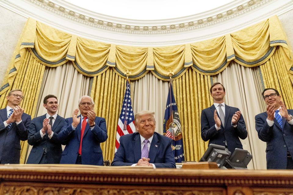 FILE - In this Aug. 12, 2020 file photo, President Donald Trump, accompanied by From left, U.S. special envoy for Iran Brian Hook, Avraham Berkowitz, Assistant to the President and Special Representative for International Negotiations, U.S. Ambassador to Israel David Friedman, President Donald Trump's White House senior adviser Jared Kushner, and Treasury Secretary Steven Mnuchin, smiles in the Oval Office at the White House in Washington. For the first time in more than a quarter-century, a U.S. president will host a signing ceremony, Tuesday, Sept. 15, between Israelis and Arabs at the White House, billing it as an "historic breakthrough" in a region long known for its stubborn conflicts. (AP Photo/Andrew Harnik, File)