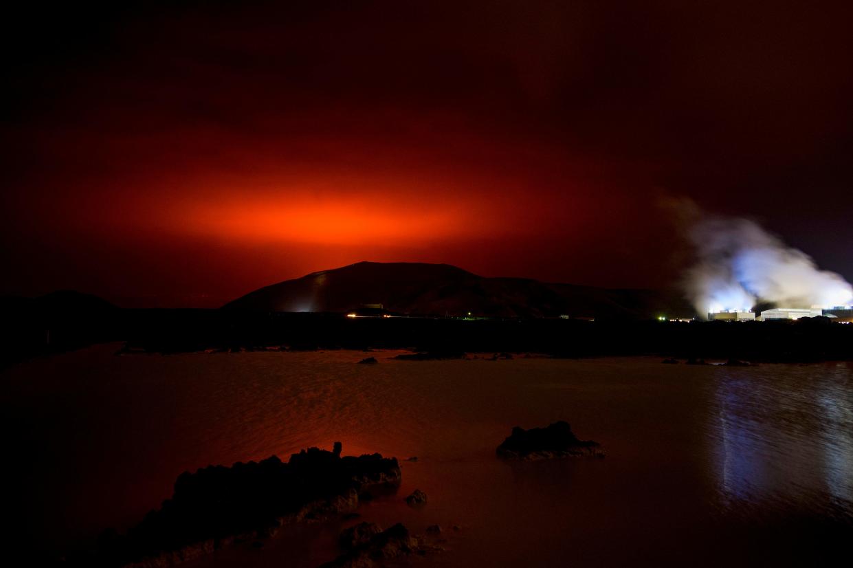 The red shimmer from magma flowing out from the erupting Fagradalsfjall volcano behind the landmark Blue Lagoon, some 45 km west of the Icelandic capital Reykjavik, on 19 March 2021 (AFP via Getty Images)