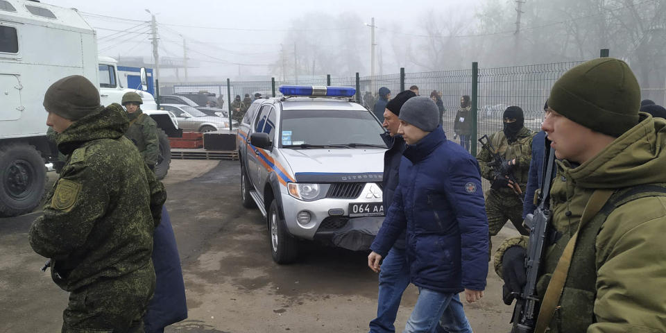 Ukrainian war prisoners escorted by Russia-backed separatist soldiers walk to be exchanged near the checkpoint Horlivka, eastern Ukraine, Sunday, Dec. 29, 2019. Ukrainian forces and Russia-backed rebels in the east have begun exchanging prisoners in a move aimed at ending their five-year-long war. (AP Photo/Alexei Alexandrov)