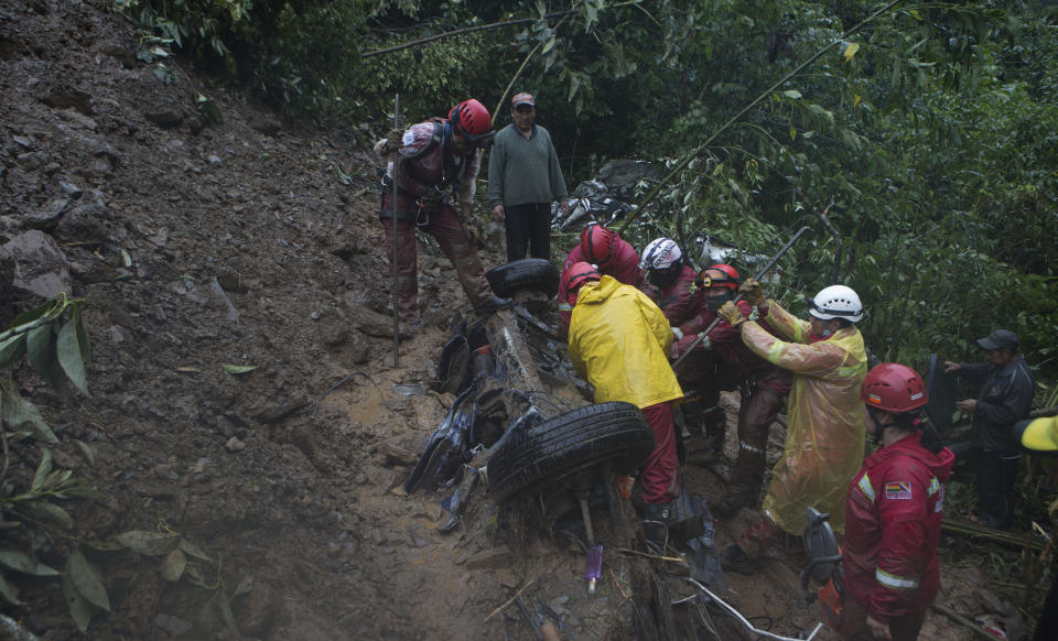 Firefighters try to rescue victims from a car after a mudslide on the outskirts of El Choro, Bolivia, Saturday, Feb. 2, 2019. According to police, at least five people died and others were injured after vehicles were dragged Saturday by a mudslide on a mountainous road in the north of La Paz. (AP Photo/Juan Karita)