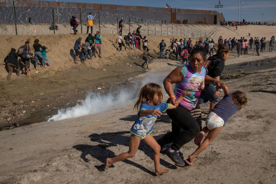 Maria Meza, 40, part of a caravan of thousands from Central America trying to reach the United States, runs away from tear gas with her five-year-old twin daughters Saira Mejia Meza (L) and Cheili Mejia Meza (R) on the US-Mexico border November 25, 2018.