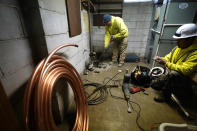 A crew breaks the concrete floor as they replace the lead water main with copper tubing at a home in Royal Oak, Mich., on Tuesday, Nov. 16, 2021. Communities with lead pipes could see higher test results for lead in their tap water if a new method of water sampling goes into effect. The Detroit suburb of Royal Oak historically had low test results but it had to notify the public of a problem after the state mandated new sampling methods. (AP Photo/Carlos Osorio)