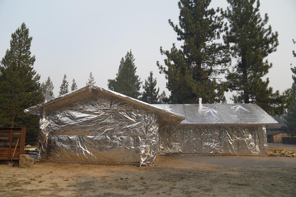 FILE - In this Sept. 1, 2021 file photo Martin Diky's home completely wrapped in fire-resistant material to protect the property against the approaching Caldor Fire in Meyers, Calif. Diky decided to order $6,000 worth of aluminum protective covering to wrap his home near Lake Tahoe in June as the last big wildfire roared through the Sierra dozens of miles southwest of the forested alpine waters. (AP Photo/Jae C. Hong,File)