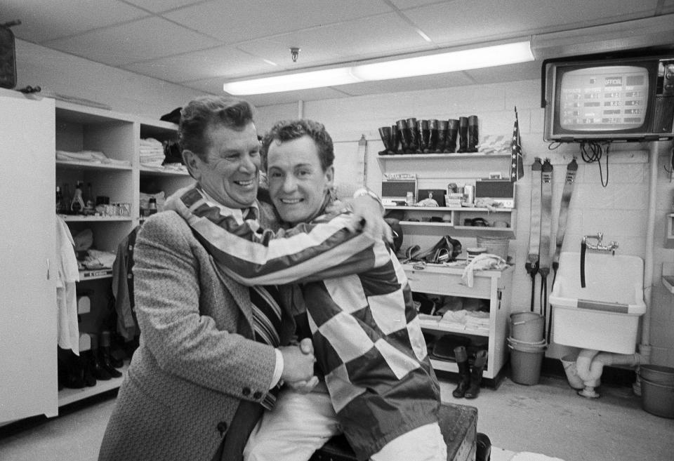 FILE - Warren C. Mehrtens, left, winner of horse racing's Triple Crown with Assault in 1946, hugs jockey Ron Turcotte in the Belmont Park jockey room after Turcotte and Secretariat won the Belmont Stakes and the 1973 Triple Crown, June 9, 1973. (AP Photo/John Rooney, File)