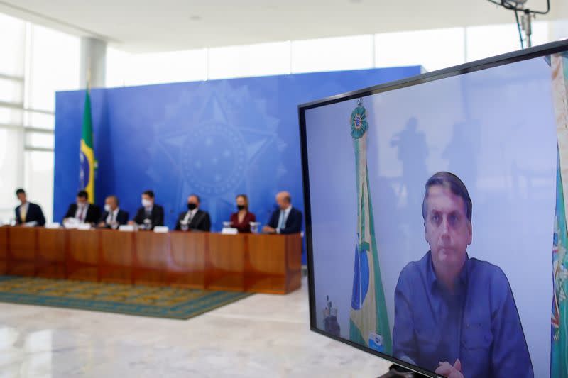 Brazil's President Jair Bolsonaro is seen on a screen as he attends via video a conference of the launching ceremony of the basic sanitation legal framework at the Planalto Palace, in Brasilia