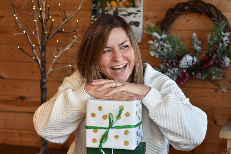 Professional gift wrapper Rachael Wood resting her hands on presents and smiling. (SWNS)