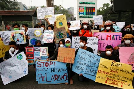 Youths gather with placards during a Global Climate Strike rally as smog covers the city due to the forest fires in Palangka Raya