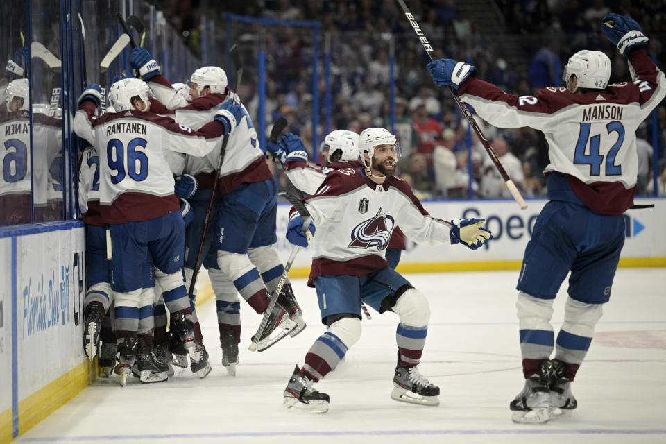 Colorado Avalanche center Andrew Cogliano, center, and defenseman Josh Manson (42) celebrate the overtime goal by teammate center Nazem Kadri (91) in Game 4 of the NHL hockey Stanley Cup Finals against the Tampa Bay Lightning on Wednesday, June 22, 2022, in Tampa, Fla. (AP Photo/Phelan Ebenhack)