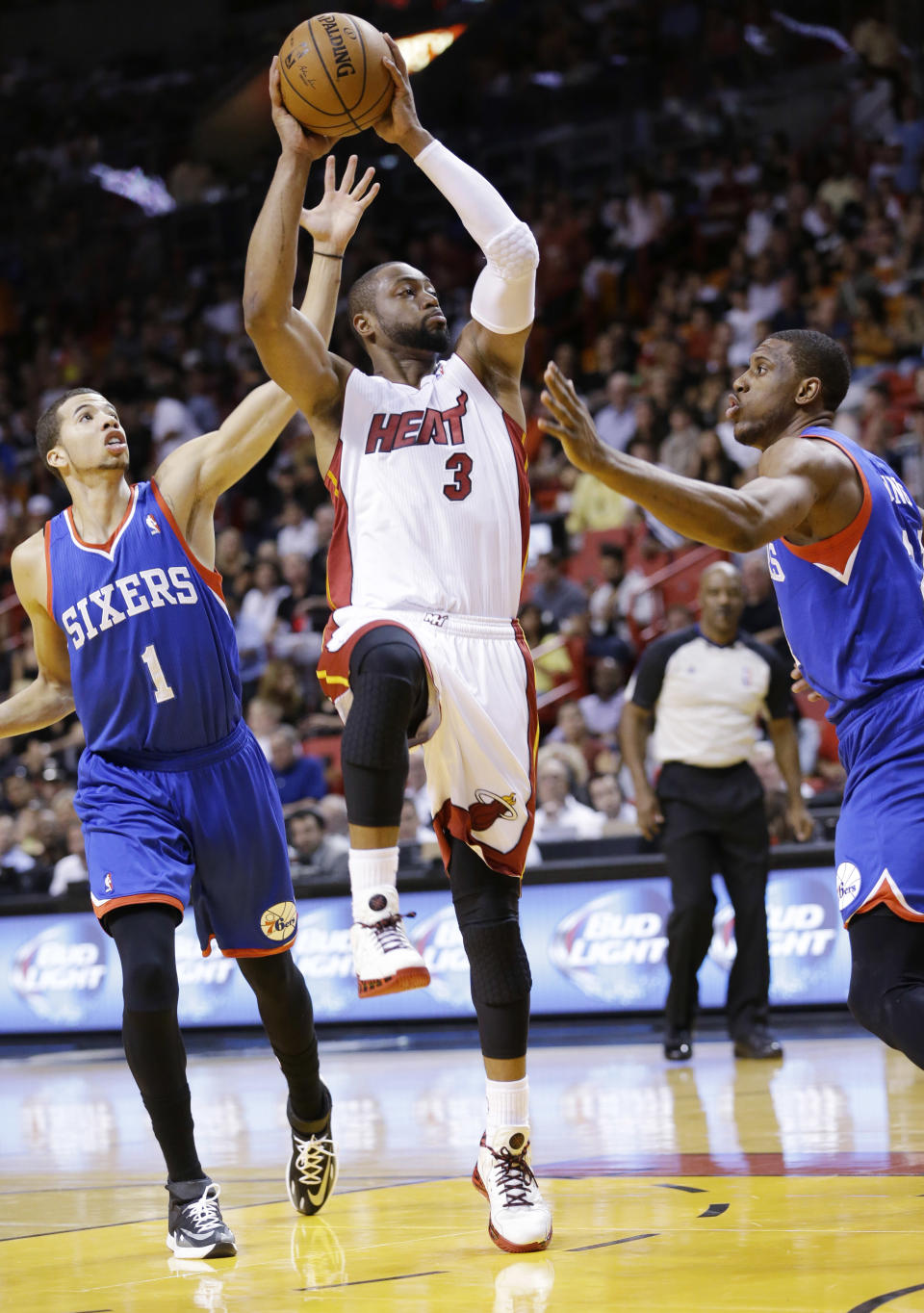 Miami Heat guard Dwyane Wade (3) goes up to shoot against Philadelphia 76ers guard Michael Carter-Williams (1) and forward Thaddeus Young, right, during the first half of an NBA basketball game on Wednesday, April 16, 2014, in Miami. (AP Photo/Wilfredo Lee)