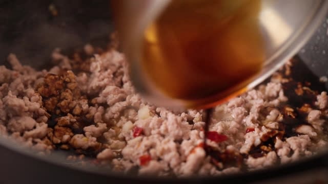 Pouring seasoning sauce into frying pork