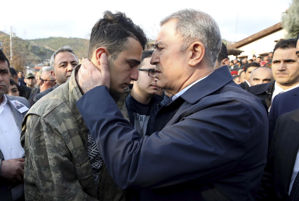 Turkey's Defence Minister Hulusi Akar speaks with brother of Halil Ibrahim Akkaya, no name available, one of Turkish soldiers killed in Syria, in Bahce, Osmaniye, Turkey, Turkey, Friday, Feb. 28, 2020. NATO envoys were holding emergency talks Friday at the request of Turkey following the killing of 33 Turkish soldiers in northeast Syria, as scores of migrants gathered at Turkey's border with Greece seeking entry into Europe. (AP Photo)