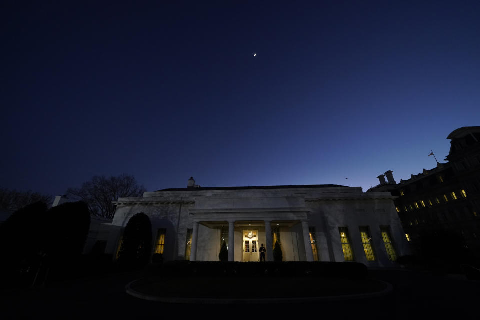 The moon rises over the West Wing of the White House, on President Donald Trump's last day in office, Tuesday, Jan. 19, 2021, in Washington. The Marine guard at the entrance signifies the president is in the Oval Office. (AP Photo/Gerald Herbert)