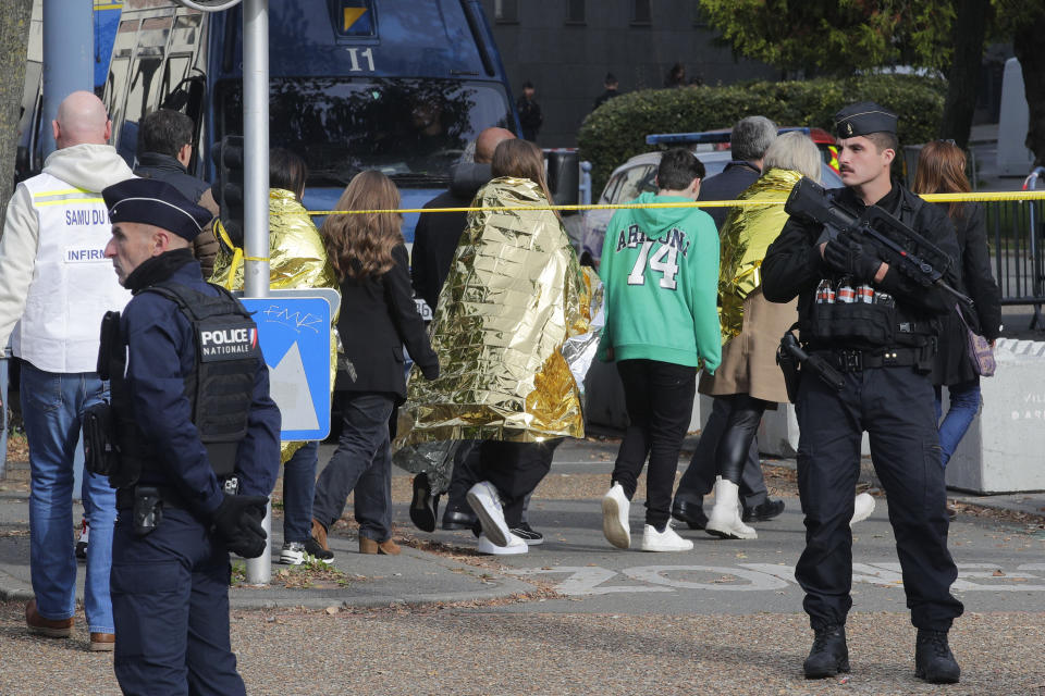 Police officers escort children outside the Gambetta high school during a bomb alert Monday, Oct. 16, 2023 in Arras, northern France. French authorities say the high school where a teacher was fatally stabbed in an attack last week has been evacuated over a bomb alert, as France's President cut short travel plans abroad to host a security meeting Monday.(AP Photo/Michel Spingler)