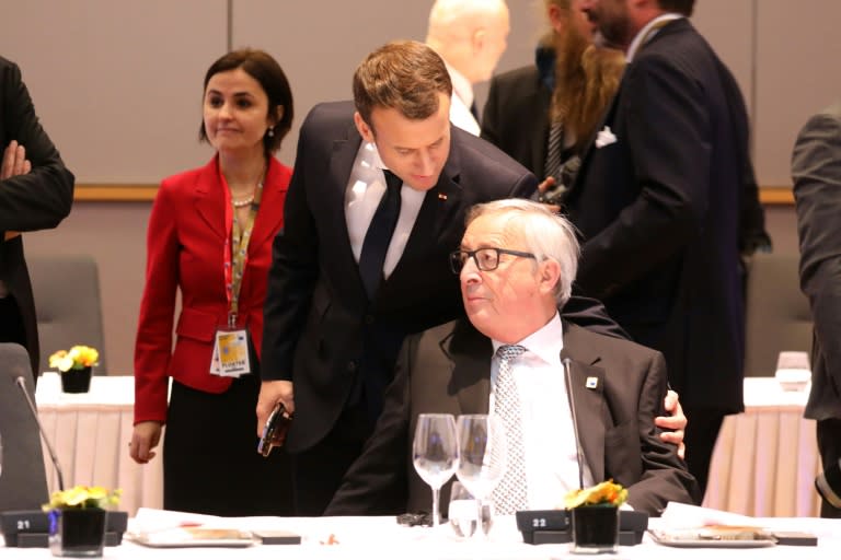 At an EU meeting, France's President Emmanuel Macron (L) talks with European Commission president Jean Claude Juncker who has warned member states that after Brexit they will have to pay more or accept cuts