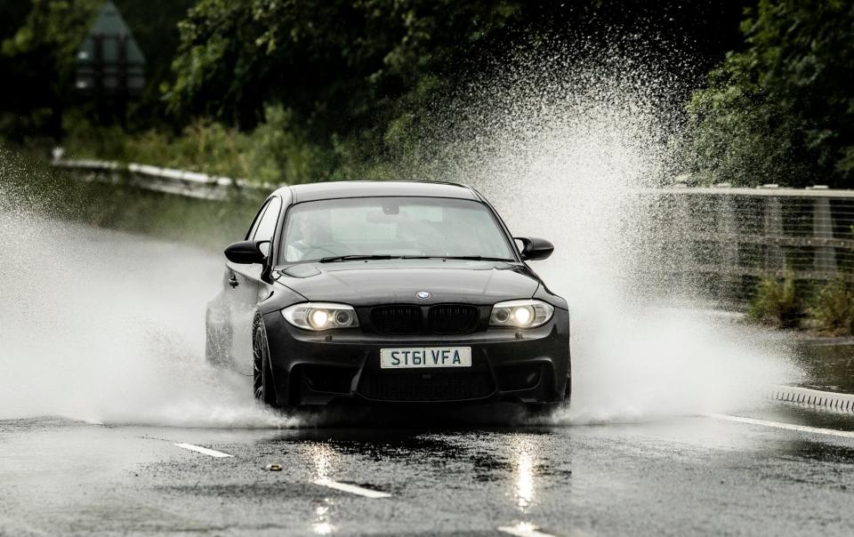 A car is driven through localised flooding near Leeming in Yorkshire. (PA)