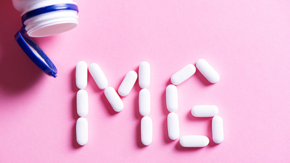 Caplets of magnesium, the best vitamin for anxiety, shaped to form the letters MG on a pink backround