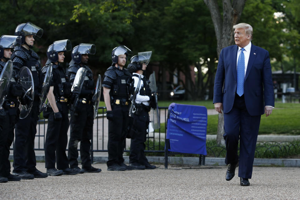 FILE - In this June 1, 2020 file photo, President Donald Trump walks past police in Lafayette Park after visiting outside St. John's Church across from the White House in Washington. An internal investigation has determined that the decision to clear racial justice protestors from an area in front of the White House last summer was not influenced by then-President Donald Trump’s plans for a photo opportunity at that spot. The report released Wednesday by the Department of Interior’s Inspector General concludes that the protestors were cleared by U.S. Park Police on June 1 of last year so new fencing could be installed. (AP Photo/Patrick Semansky)