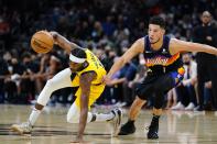 Indiana Pacers forward Justin Holiday, left, dribbles around Phoenix Suns guard Devin Booker (1) during the first half of an NBA basketball game Saturday, Jan. 22, 2022, in Phoenix. (AP Photo/Ross D. Franklin)