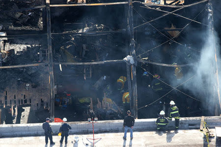 Firefighters work inside the burned warehouse following the fatal fire in the Fruitvale district of Oakland, California. REUTERS/Lucy Nicholson