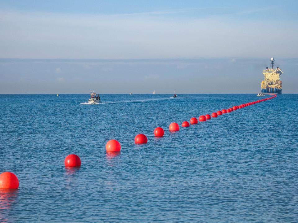 A line of buoys helps float a subsea internet cable as it's landed on the shore.