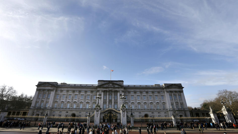 Tourists walk around Buckingham Palace in London, Tuesday, Jan. 28, 2014. British lawmakers have criticized the financial affairs of Queen Elizabeth II and her household, urging the monarch to bring in more income by opening up Buckingham Palace to visitors more often. (AP Photo/Kirsty Wigglesworth)