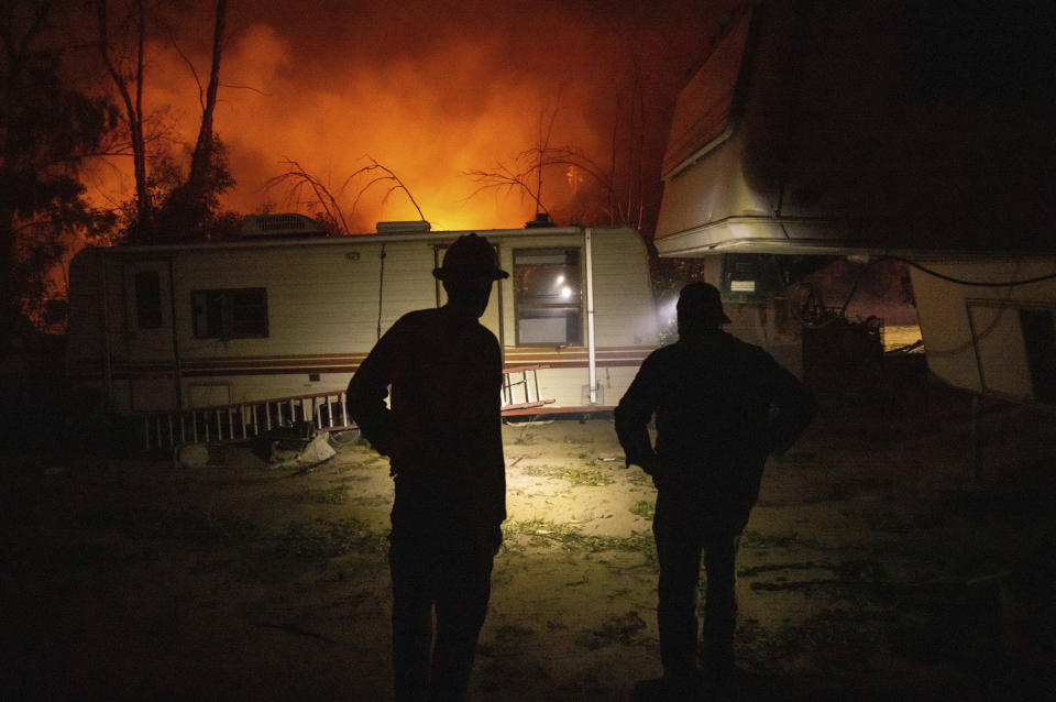 A firefighter and resident converse on how to protect his possessions as a wildfire called the Highland Fire burns in Aguanga, Calif., Monday, Oct. 30, 2023. A wildfire fueled by gusty Santa Ana winds ripped through rural land southeast of Los Angeles on Monday, forcing thousands of people from their homes, fire authorities said. (AP Photo/Ethan Swope)