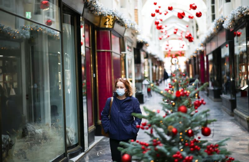 Woman walks through the Burlington Arcade adorned with Christmas decorations, in London