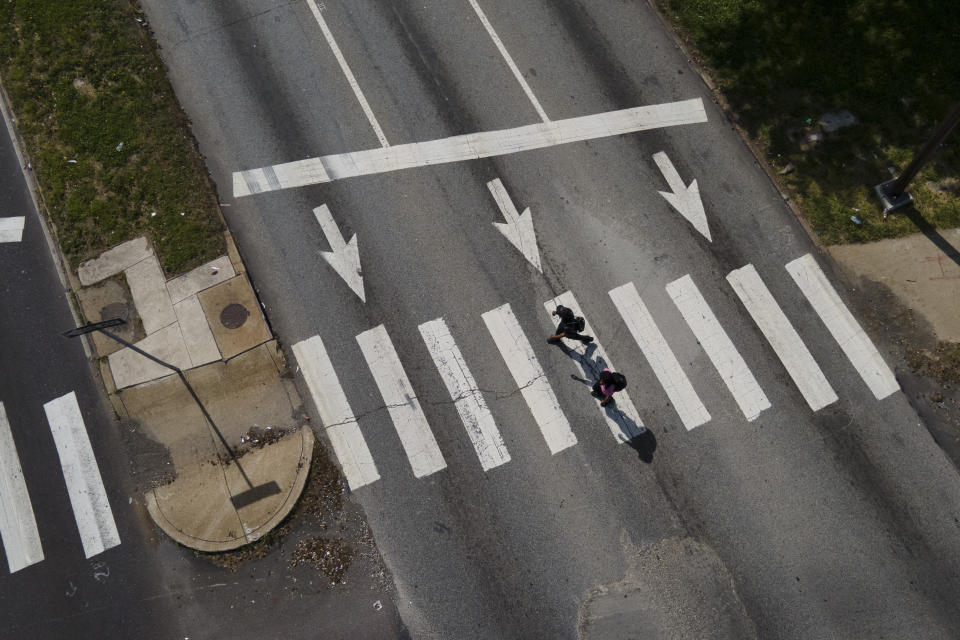 Pedestrians cross Roosevelt Boulevard at the intersection with North Mascher Ave, Thursday, May 12, 2022, in Philadelphia. Roosevelt Boulevard is an almost 14-mile maze of chaotic traffic patterns that passes through some of the city's most diverse neighborhoods and Census tracts with the highest poverty rates. Driving can be dangerous with cars traversing between inner and outer lanes, but biking or walking on the boulevard can be even worse with some pedestrian crossings longer than a football field and taking four light cycles to cross. (AP Photo/Julio Cortez)