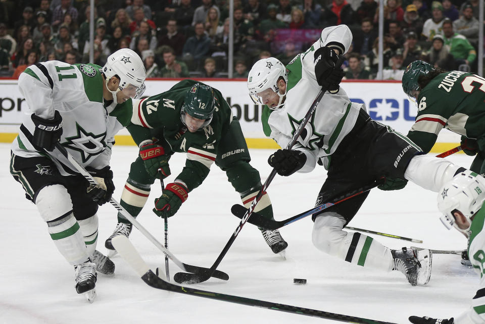 Dallas Stars' Corey Perry (10) falls to the ice while going after the puck against Minnesota Wild's Eric Staal (12) and Mats Zuccarello (36) in the second period of an NHL hockey game Saturday, Jan. 18, 2020, in St. Paul, Minn. (AP Photo/Stacy Bengs)