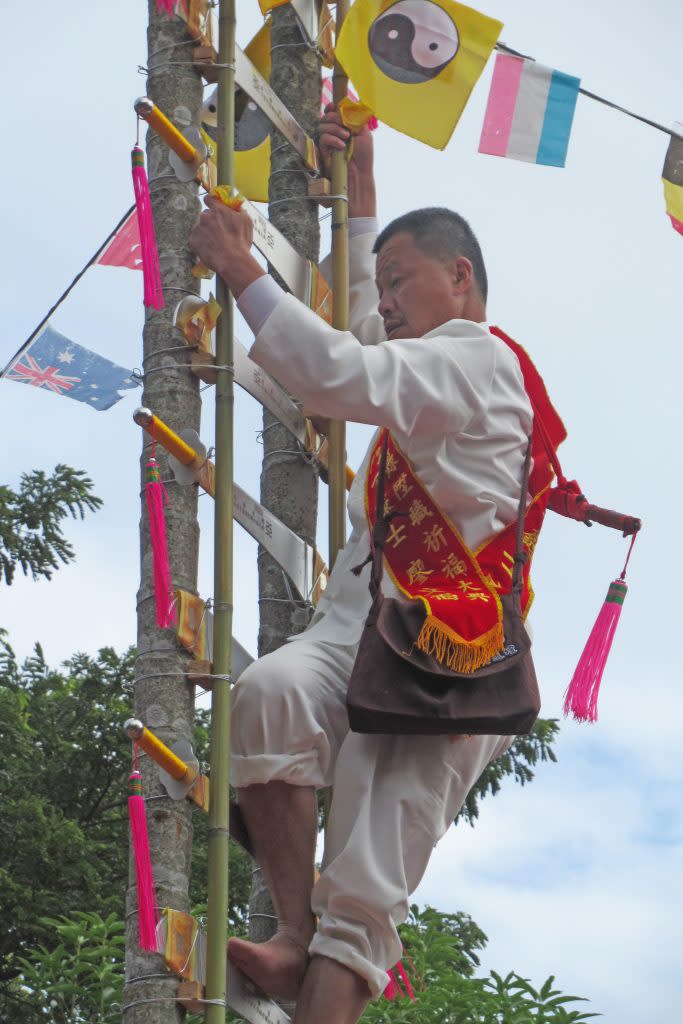 廖文福全神灌注，赤腳攀登刀梯。 （記者陳佳伶攝）