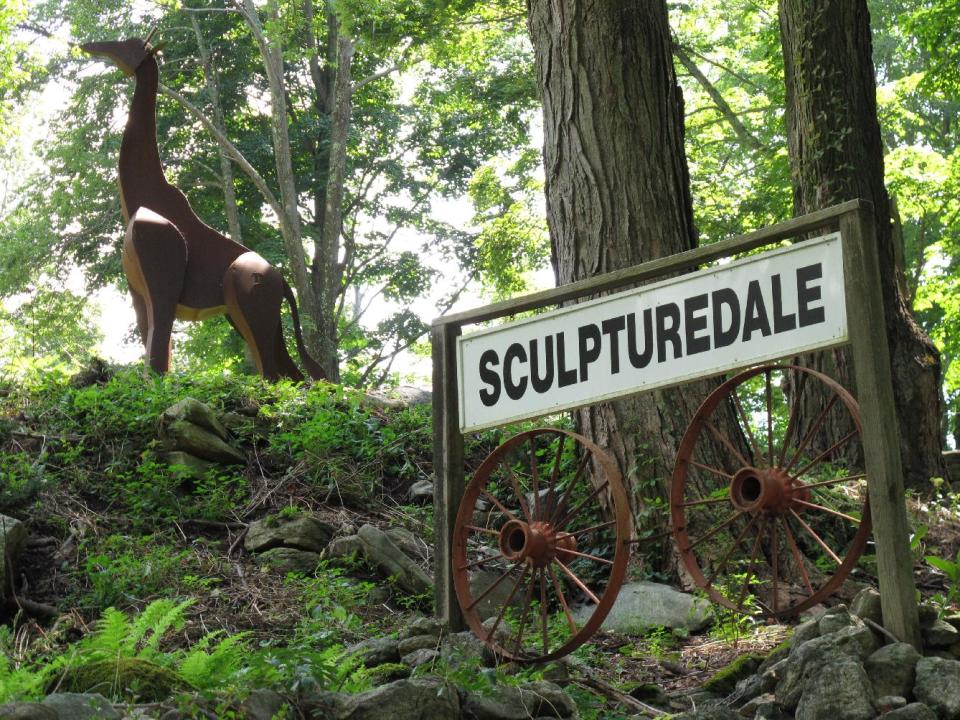 This Aug. 27, 2013 photo shows the entrance to "Sculpturedale" in Kent, Conn., where artist Denis Curtiss creates massive steel animals - panthers, elephants and giraffes - that loom among the trees along his property on Route 7. Curtiss has been making the cubist style sculptures for decades. (AP Photo/Helen O'Neill)