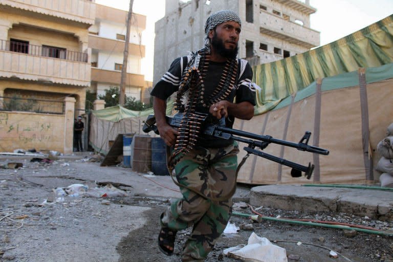 An opposition fighter runs across a street in the industrial area of Syria's eastern town of Deir Ezzor during clashes with regime forces on September 12, 2013