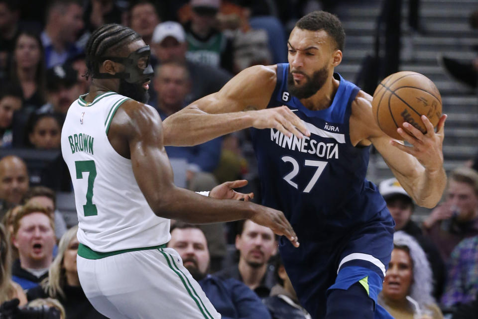 Minnesota Timberwolves center Rudy Gobert (27) goes to the basket against Boston Celtics forward Jaylen Brown (7) during the third quarter of an NBA basketball game Wednesday, March 15, 2023, in Minneapolis. The Celtics won 104-102. (AP Photo/Bruce Kluckhohn)