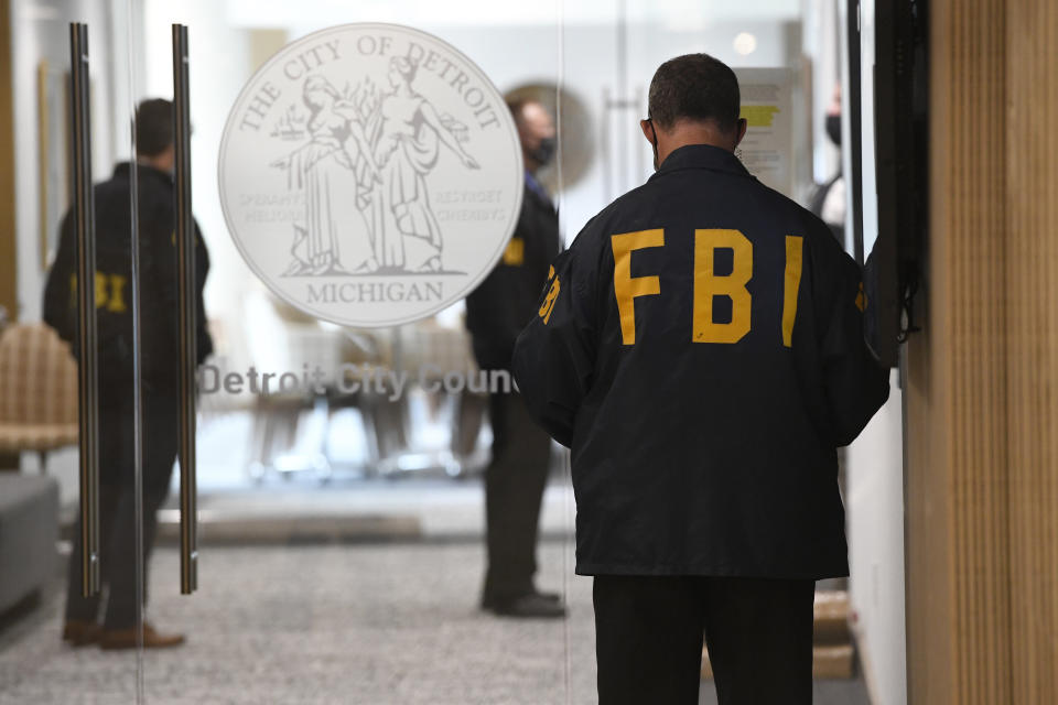 An FBI employee guards the entrance doors to the Detroit City Council on the 13th floor of the Coleman A. Young Municipal Center, Thursday, Aug. 25, 2021, in Detroit. Federal agents searched the homes of two Detroit City Council members, Janeé Ayers and Scott Benson, and city offices Wednesday, just a few weeks after another official was charged in an alleged bribery scheme. (Jose Juarez/Detroit News via AP)