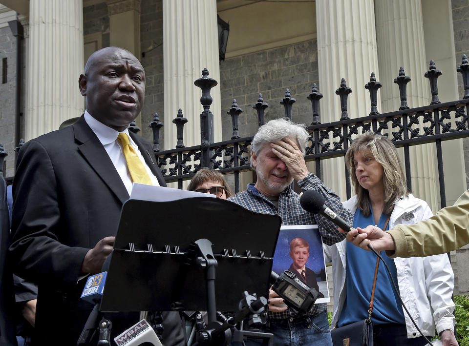 Attorney Ben Crump, left, along with clergy abuse victim Marc Floto of Westminster, standing with his wife, Melissa, right, speaks, during a news conference, Tuesday, May 9, 2023, in Baltimore. He is holding a photograph of himself as a child. After Maryland lawmakers recently passed legislation eliminating the statute of limitations for child sex abuse lawsuits amid increased scrutiny of the Archdiocese of Baltimore, civil rights attorney Ben Crump announced a series of civil claims Tuesday he plans to bring on behalf of victims. (Barbara Haddock Taylor/The Baltimore Sun via AP)