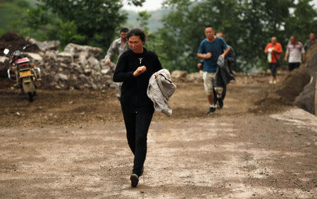 People run past a hillside alley which is at risk of landslide after an earthquake hit Ludian county of Zhaotong, Yunnan province August 3, 2014. REUTERS/China Daily